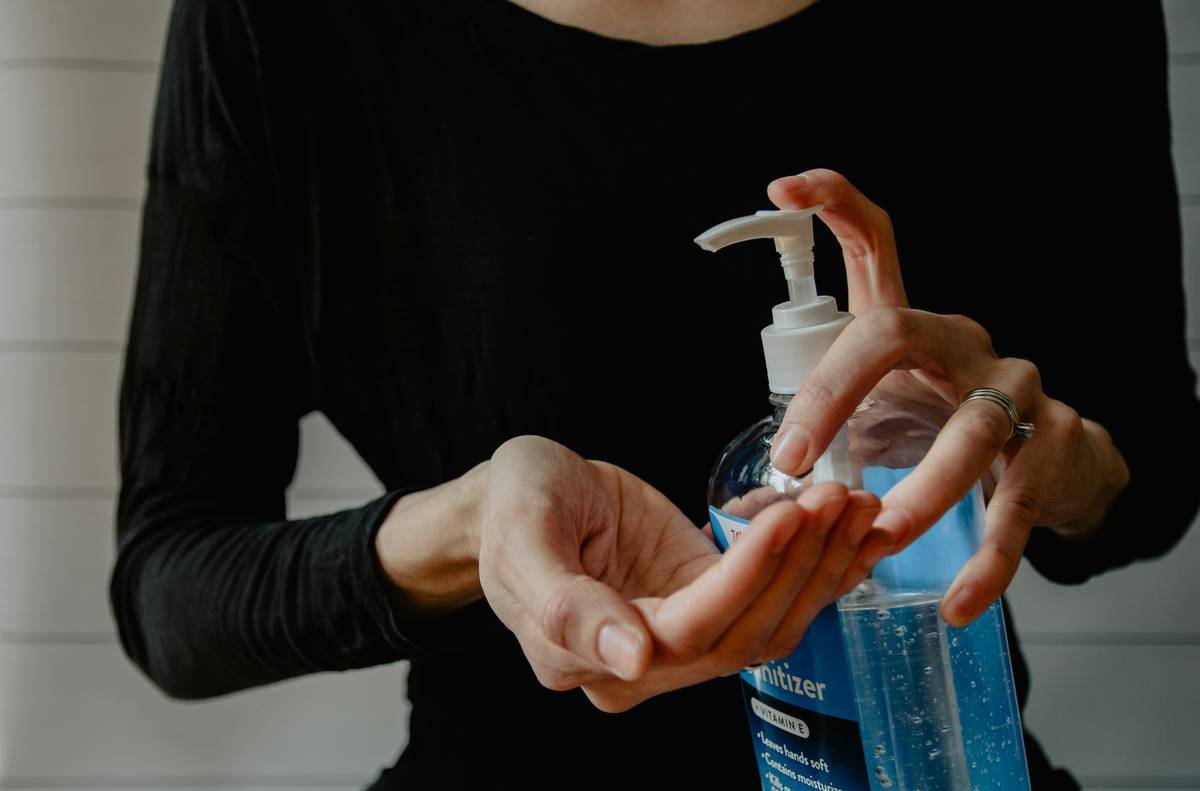 A close-up shot of a bottle of plant-based moisturizer surrounded by fresh herbs.
