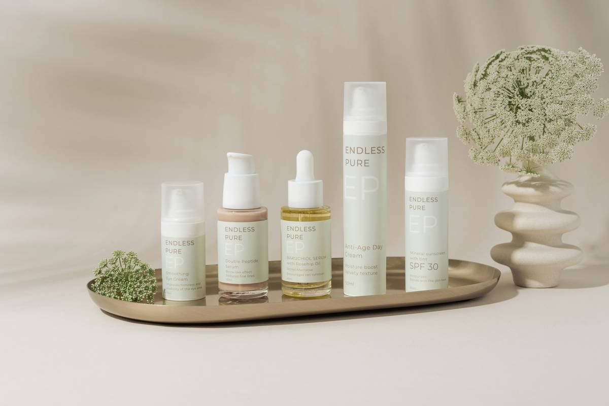 A beautifully arranged display of elegant skincare products on a marble tray against a soft, beige backdrop. The collection includes various bottles and jars, showcasing a range of serums, creams, and SPF protection. The minimalist design and soft pastel colors create a clean, luxurious aesthetic. A delicate floral arrangement in a textured vase adds a natural touch to the composition, enhancing the serene and sophisticated vibe.