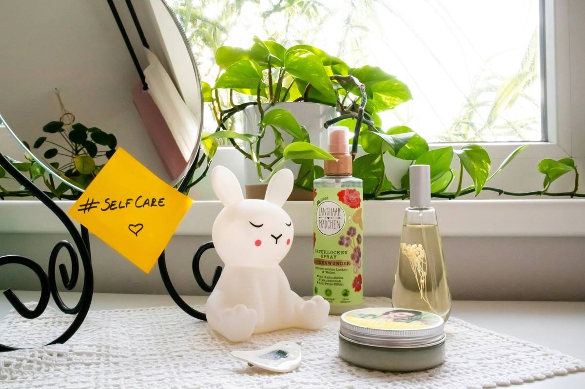 Dresser with cosmetic products and a mirror with a sticky note with the hashtag #selfcare on it