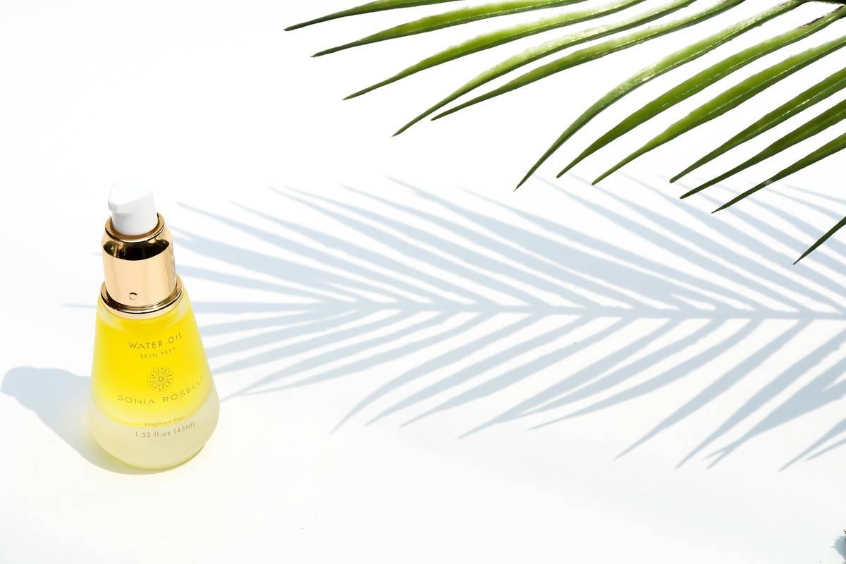 Sonia Roselli Water Oil Facial Moisturizer in the summer with leaves and shadow.